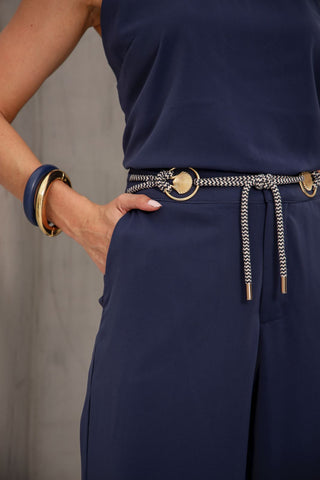Navy blue outfit with a belt and gold accents on a neutral background
