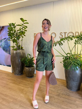 Woman in a green dress standing in front of plants and a wall with text